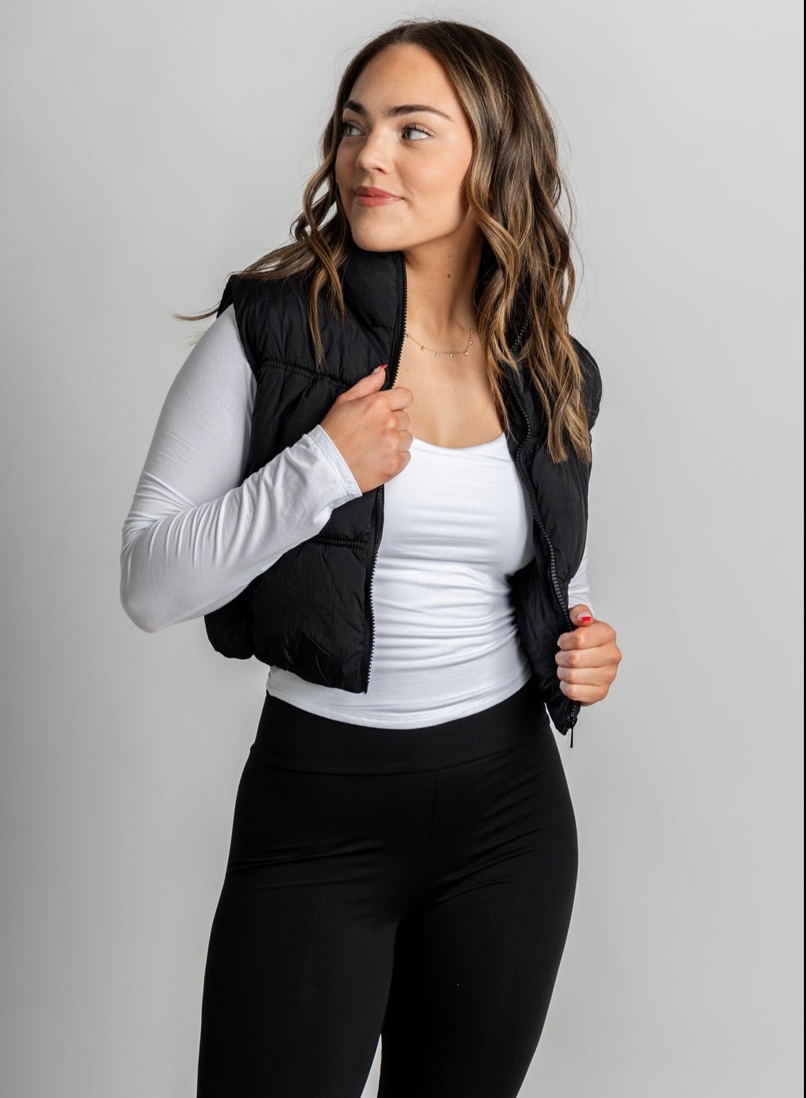 Black puffer vest from Lush Fashion Lounge boutique layered over a basic white long sleeve top 